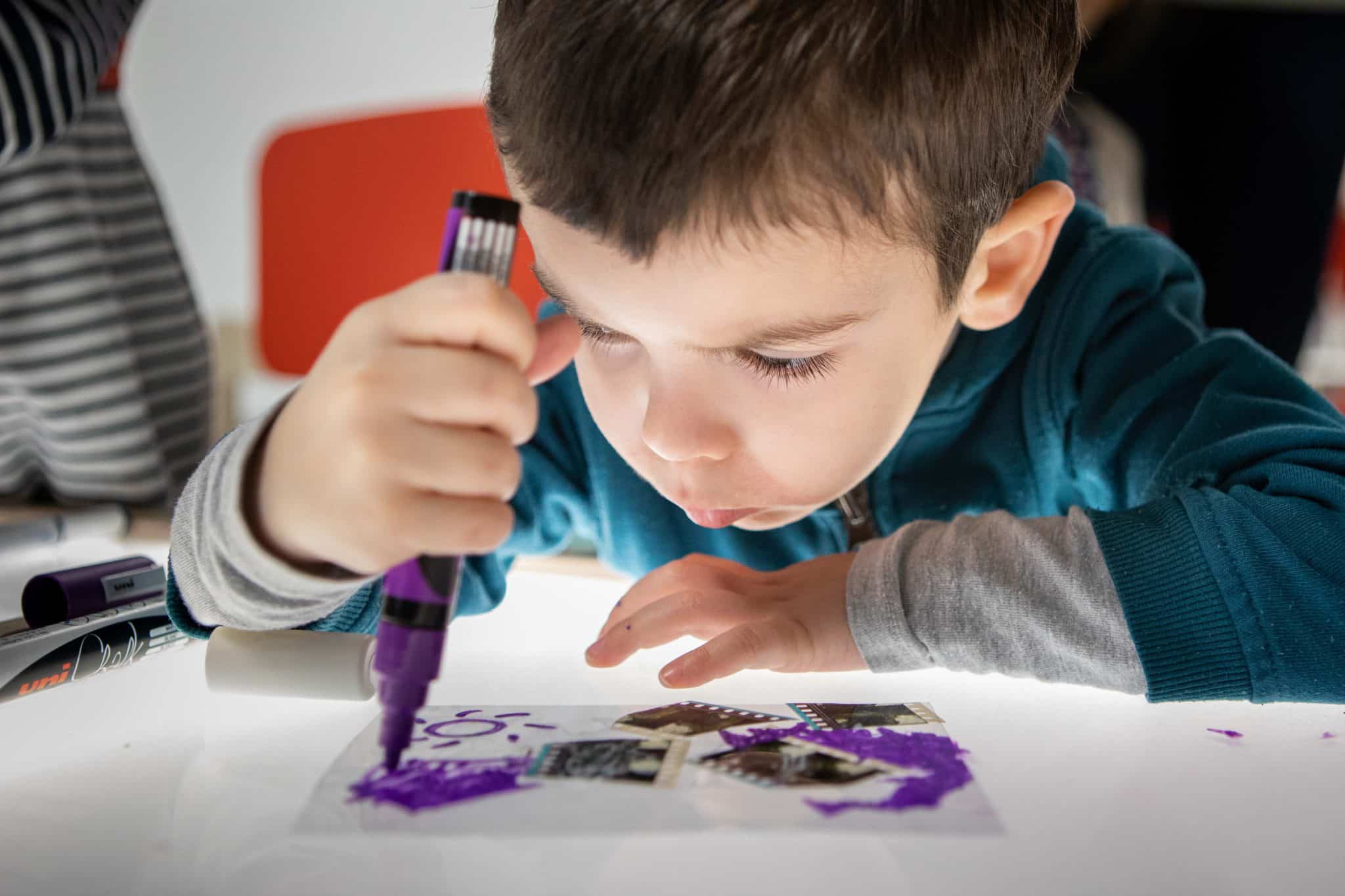 Un enfant en gros plan dessine dans le cadre des Petits Ateliers