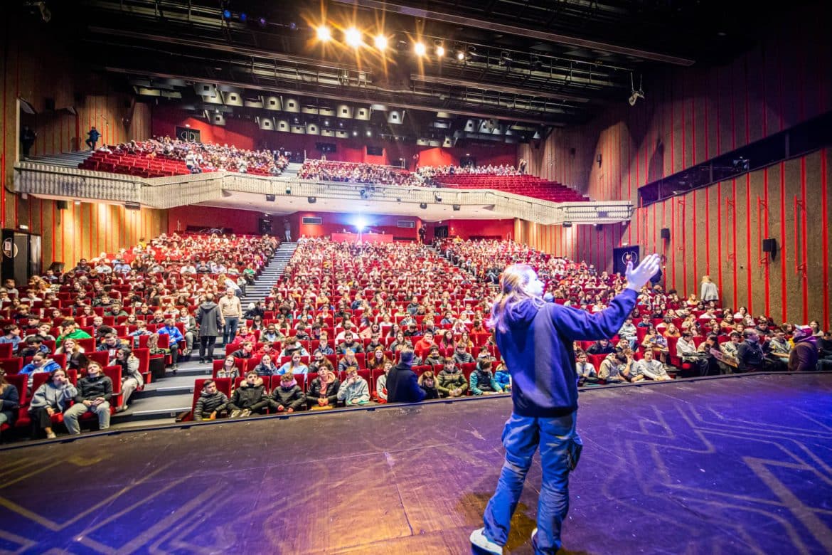Public scolaire vu de face avec intervenant sur scène