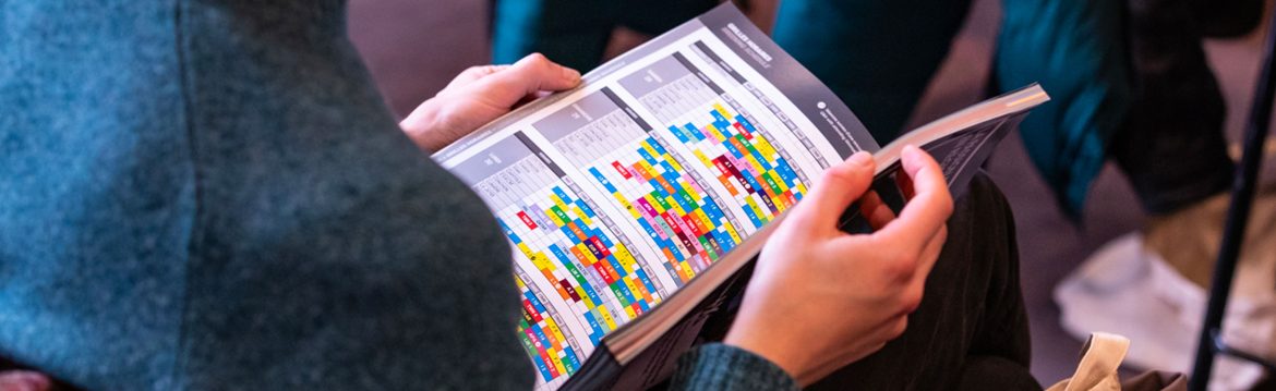 Une personne feuillette le catalogue du festival