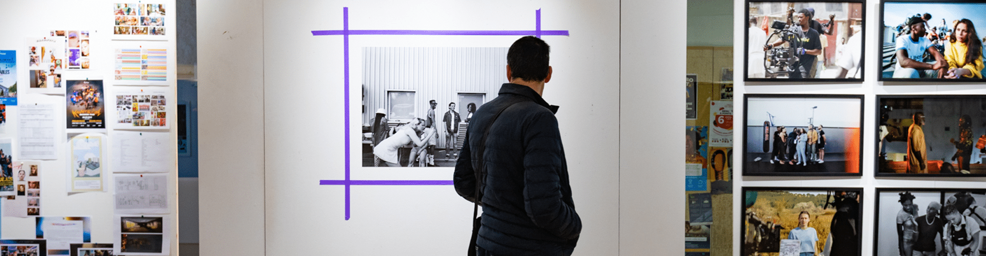 Un homme passe devant plusieurs photographies mises en valeur dans le cadre d'une exposition du festival